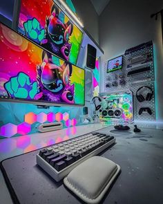 a computer desk with a keyboard, mouse and headphones on it in front of a colorful wall