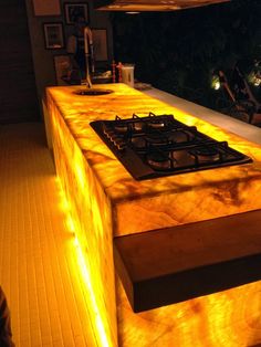 a kitchen counter that has some lights on top of it and is lit up in the dark