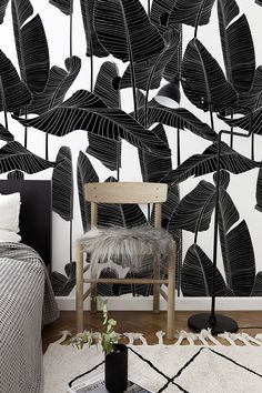 a black and white wallpaper with large leaves on it in the corner of a bedroom