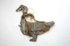 an animal made out of old pieces of paper and rope on a white surface with some string attached to it