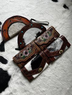 two cow hide purses sitting on top of a white and black fur covered floor