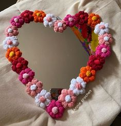 a heart shaped mirror with crocheted flowers on it