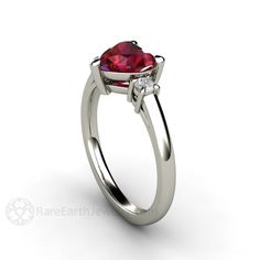 A sweetheart of a ring, a gorgeous 3 stone Ruby and diamond ring available in your choice of 14K or 18K White, Yellow or Rose Gold. At the center is a 1.70ct lab grown heart cut Ruby. Two sparkling conflict free diamonds surround it, .20cts total weight. So pretty! Ruby is the birthstone for July. This ring would make a beautiful engagement ring. A matching wedding band is available. Inquire for pricing. Lab grown Rubies are physically, chemically and optically identical to natural Rubies. The R Engagement Ring Heart, Ring 3 Stone, Heart Shaped Diamond Ring, August Birthstone Necklace, Red Gemstone Ring, Heart Promise Rings, Ruby And Diamond Ring, Ruby Birthstone, Ring Ruby