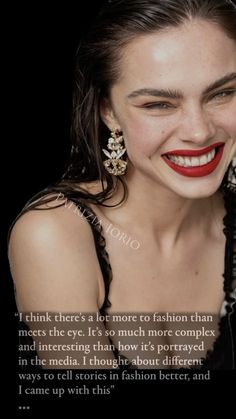 a woman with red lipstick and statement earrings on her head, smiling at the camera text reads i think there's a lot more to fashion than