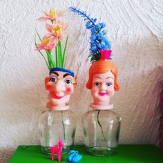 two plastic head vases sitting on top of a green table