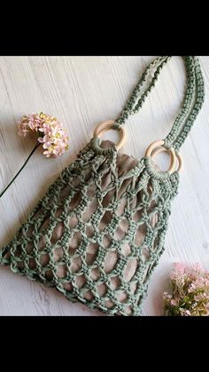 a crocheted bag sitting on top of a white table next to a flower