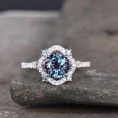 a blue and white diamond ring sitting on top of a rock