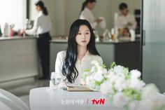 a woman sitting at a table with flowers in front of her