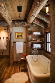 a bathroom with wood floors and exposed ceiling, white bathtub in the center surrounded by wooden beams