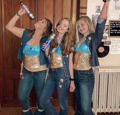 three young women dressed in blue and gold holding up bottles with their hands, standing next to each other