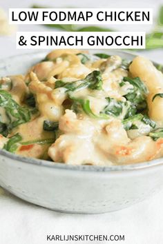 a white bowl filled with pasta and spinach on top of a table next to other food