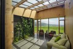 a living room filled with lots of furniture next to a large window covered in plants