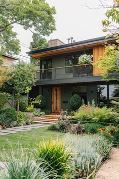 a house that is surrounded by trees and flowers in the front yard with lots of greenery