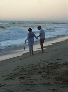 two people standing on the beach holding hands