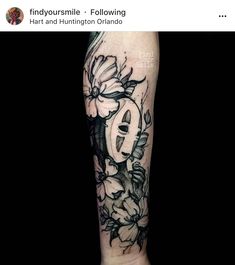 a black and white tattoo with flowers on the arm