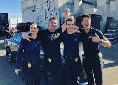 three police officers posing for a photo in front of a car