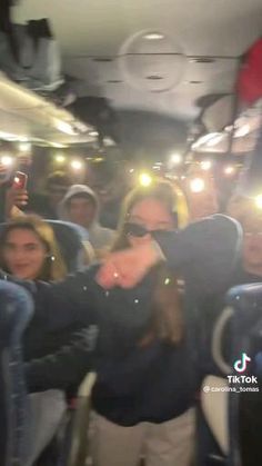 a group of people riding on the back of a bus with their hands in the air