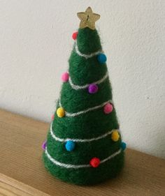 a small felt christmas tree sitting on top of a wooden table