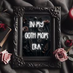 an old frame with the words in my goth mom era written on it next to roses