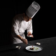 a chef is preparing food on a plate with spoons and utensils in front of him