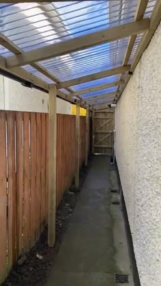 a long narrow alley with wooden slats on the sides and concrete flooring along one side