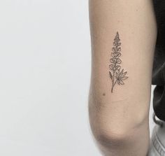 a woman's arm with a small flower tattoo on the left side of her arm