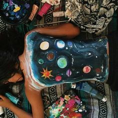 a woman is laying on the ground with her body painted like an art project and surrounded by other arts and crafts supplies