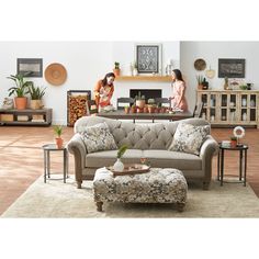 two women sitting on a couch in a living room with a coffee table and ottoman