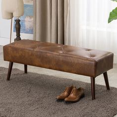 a brown leather bench sitting on top of a rug next to a pair of shoes