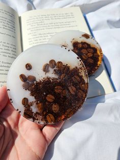 a person holding an open book with some food on top of it and coffee beans in the middle