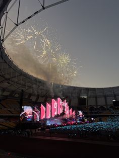 fireworks are lit up in the night sky above a stadium's stage and crowd