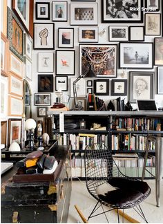 a room filled with lots of framed pictures on the wall next to a desk and chair