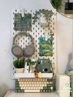 a computer keyboard sitting on top of a desk next to a potted plant and mirror