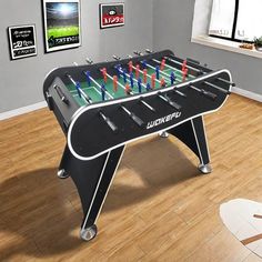 a foosball table in the middle of a living room with pictures on the wall