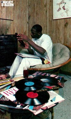 a man sitting in a chair next to a pile of records