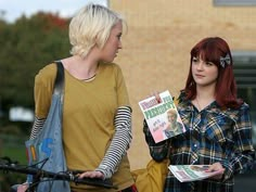 two women standing next to each other holding books