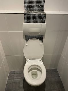 a white toilet sitting in a bathroom next to tiled walls