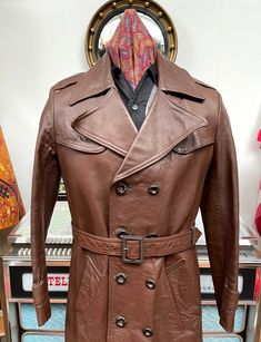 Top quality Vintage men's trenchcoat from the fabulous 1970s. No makers label although it could possibly be  Hepworths for Hardy Amies. Nice conker brown colour,thick leather,fab wide highwaymans colour measuring near 6"inches,front panel consisting of 8 buttons,epaulets in the shoulders and cuffs are just for show and do not unbutton,fab rear vent is an impressive 16&1/2" inches and overall apart from the left side this coat is in great condition,looks like the fella who owned this had a fall a Retro Brown Double-breasted Outerwear, Vintage Brown Long Coat, Vintage Double-breasted Outerwear, Fitted Retro Vintage Brown Outerwear, Retro Brown Outerwear For Vintage Fashion, Retro Vintage Brown Outerwear With Button Closure, Fitted Vintage Outerwear With Belt Loops, Vintage Fitted Belted Outerwear, Fitted Vintage Belted Outerwear