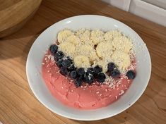 a cake with blueberries and bananas is on a white plate next to a wooden table