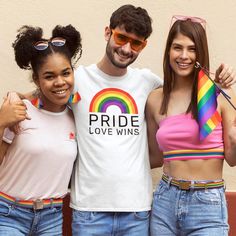 two women and a man wearing pride love wins t - shirts posing for the camera