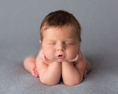 a baby is laying on its back with his hands under his chin and eyes closed