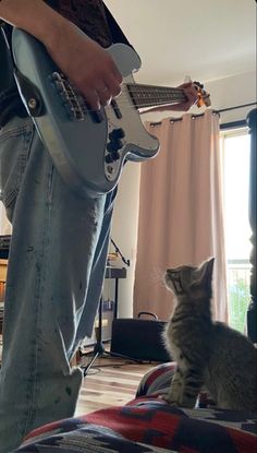 a person playing guitar with a cat looking on