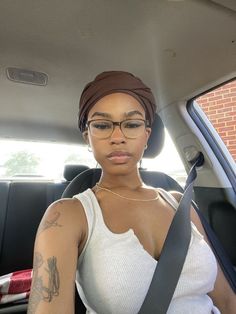 a woman sitting in the back seat of a car wearing glasses and a turban