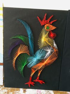 a colorful rooster made out of wire on a black background