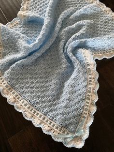 a blue crocheted blanket laying on top of a wooden floor