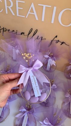 a hand holding a purple ribbon over some wine glasses with tags on them that say creation