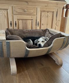 a dog laying in a bed on top of a wooden floor