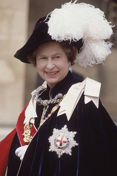 an older woman wearing a black and white outfit with feathers on her head, standing in front of a building