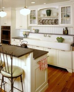 a kitchen with white cabinets and black counter tops, an island with four chairs in it