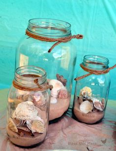 three glass jars with sand, seashells and rope